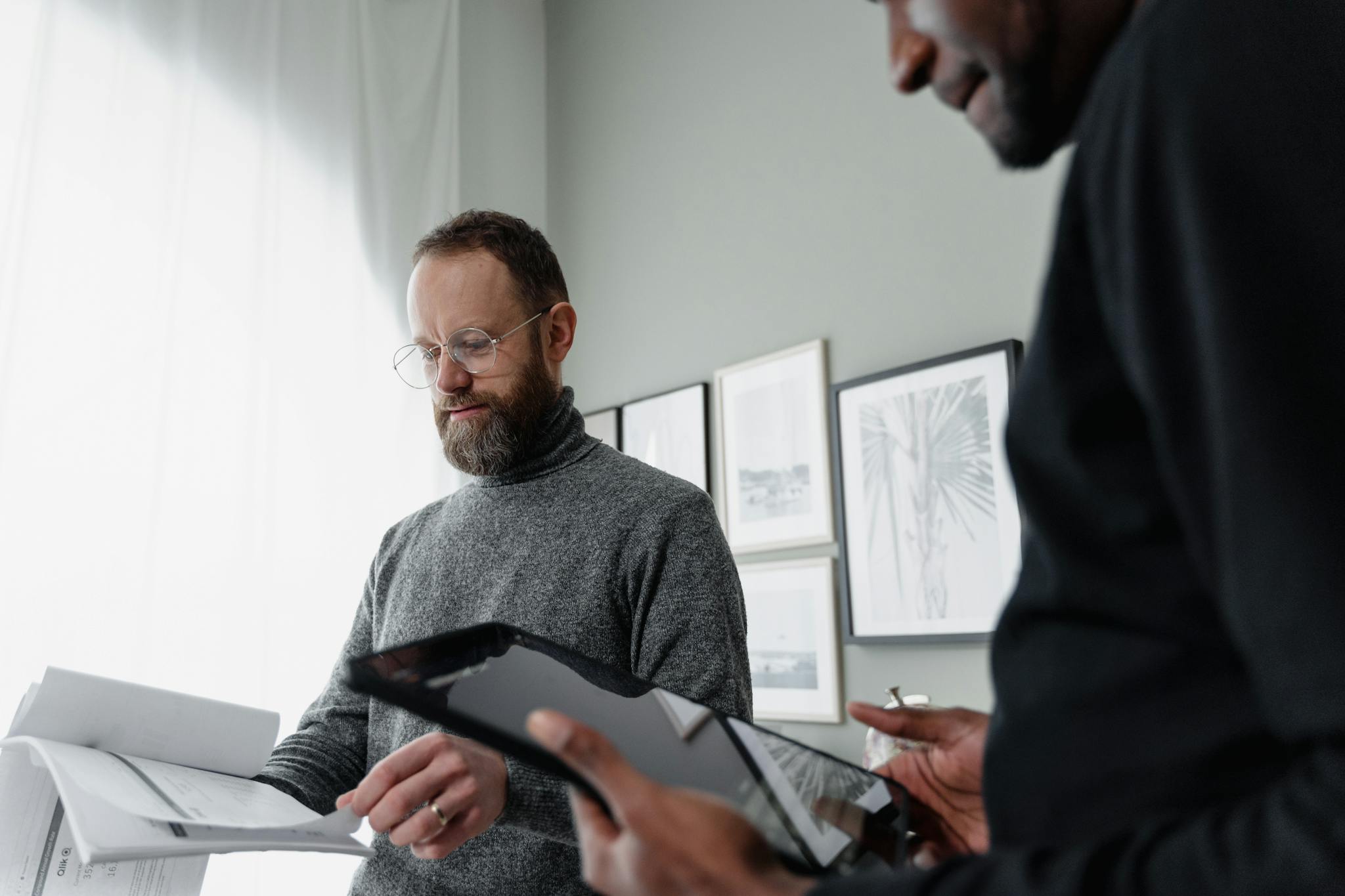 Two professionals engaged in a focused meeting with papers and tablets indoors.